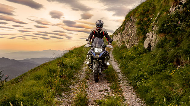 Scène de conduite avec la BMW R 1250 GS Adventure en montagne sur un chemin de terre